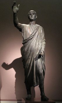 Aule Metele Romano-Etruscan工作在罗马风格,描绘了一个伊特鲁里亚人穿着短罗马宽外袍和鞋类。右臂抬起,表明他是一个演说家解决公众。维基共享。